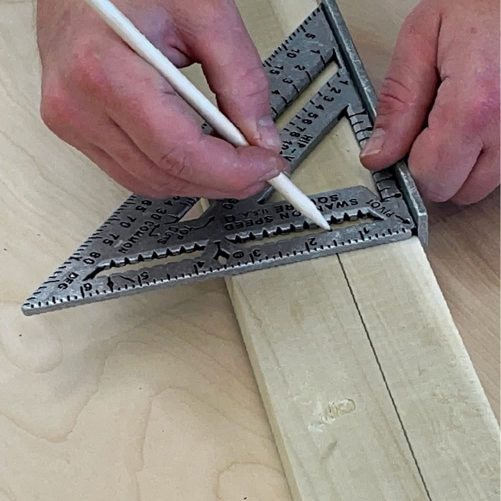 A Swanson Speed® Square PRO being used with a white pencil to scribe the width of a 2X stud along the 1½ in. base edge.