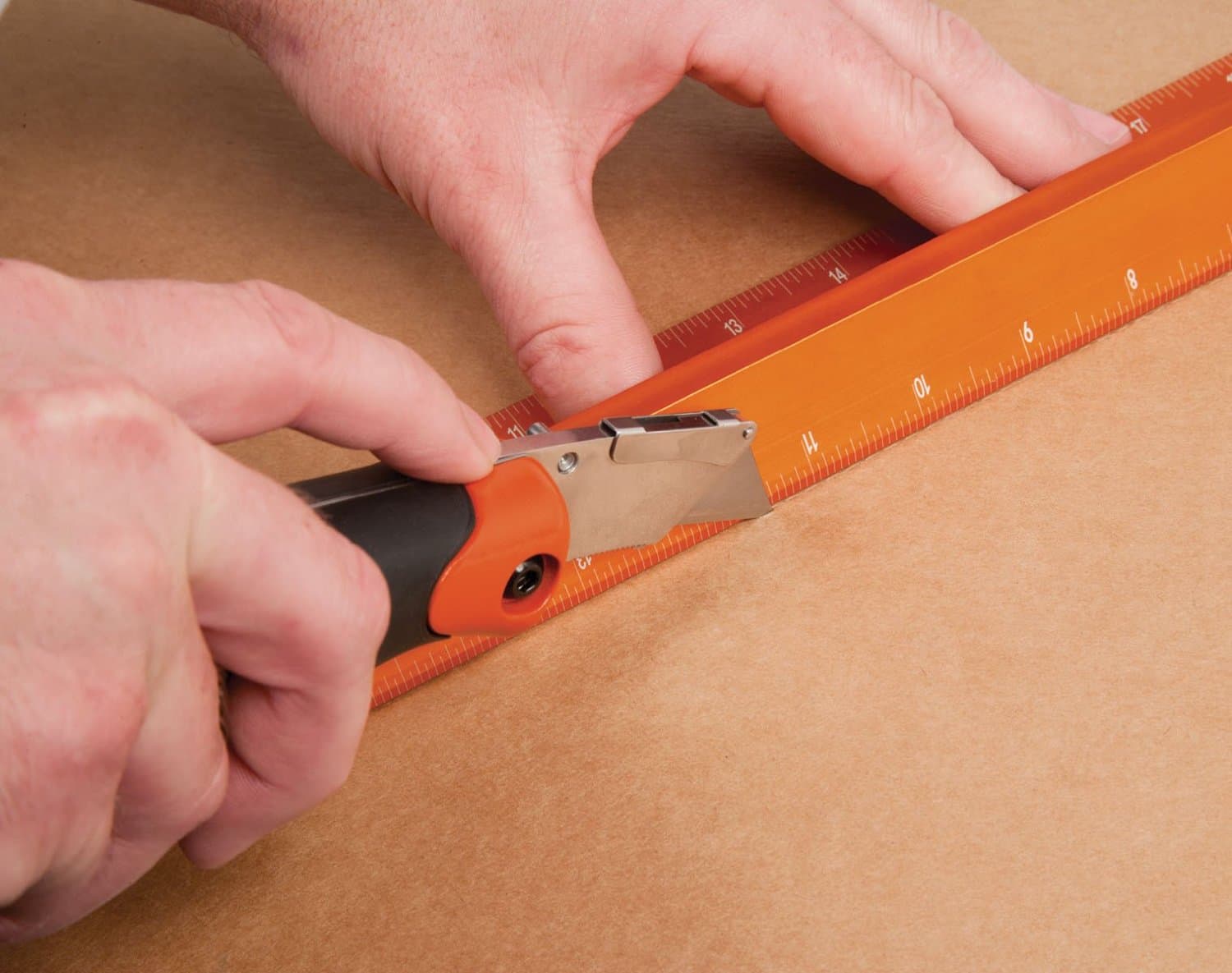 Hands using a utility knife along the SAVAGE 36 in. No Slip Straight Edge, blade caught by the raised Thumb Saver edge.