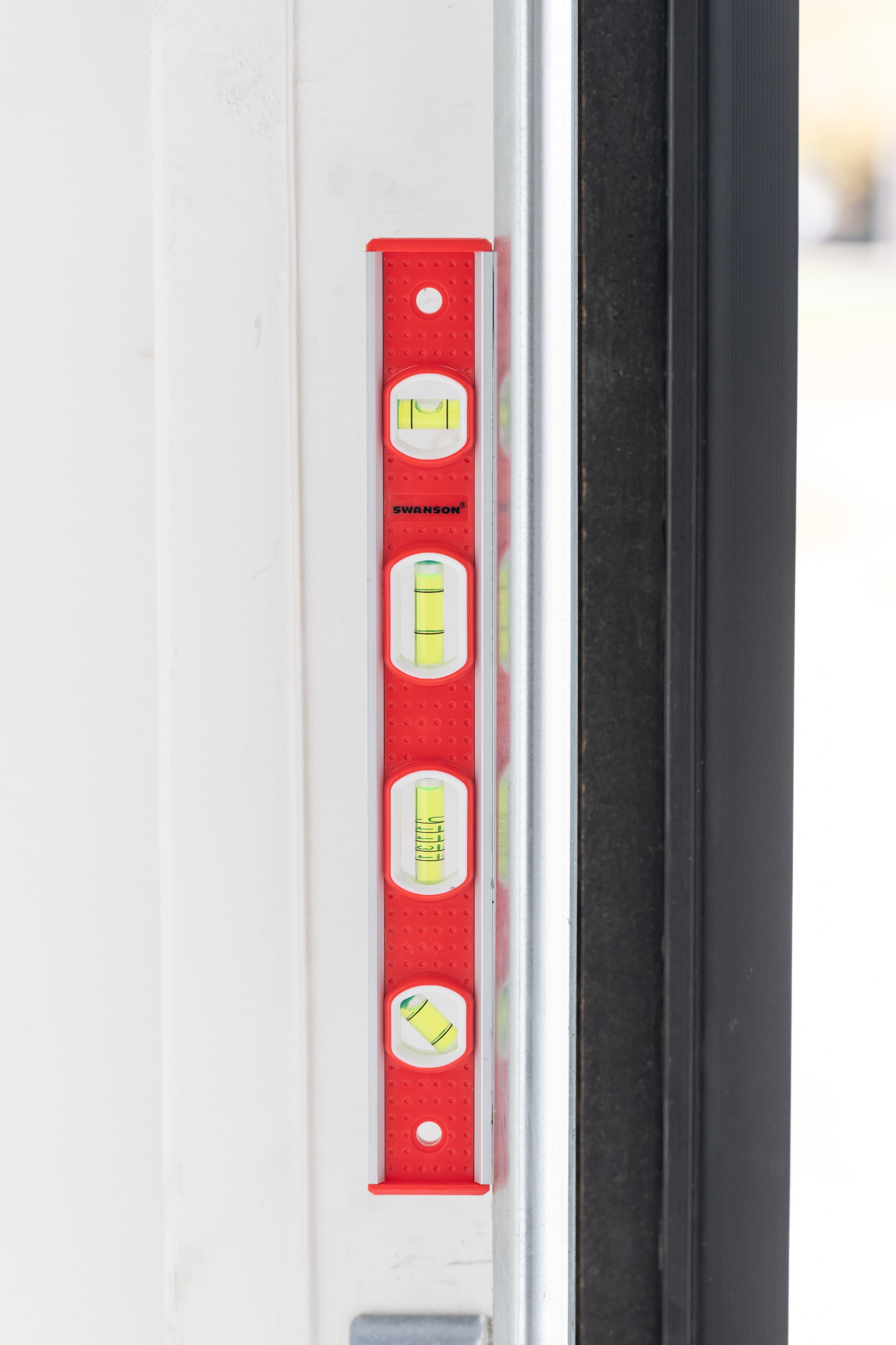 The Swanson TBL001M Tool Box Level standing on a door jamb, reading plumb.