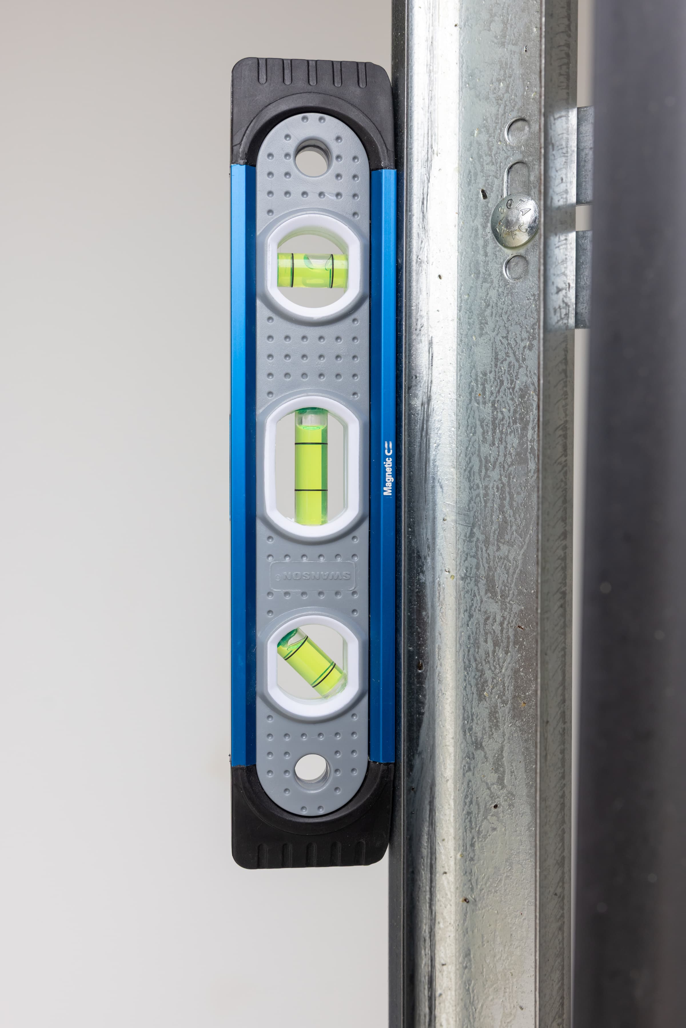 A trades pro using the Swanson TL009M Magnetic Shock-Resistant Torpedo Level on a ferrous job-site surface.
